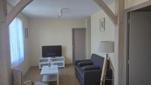 a living room with a couch and a tv at Résidence Mauriac in Mauriac