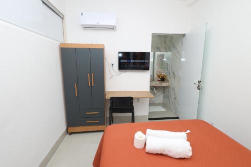 a bedroom with a bed and a desk with a computer at Pousada House Garden in Goiânia
