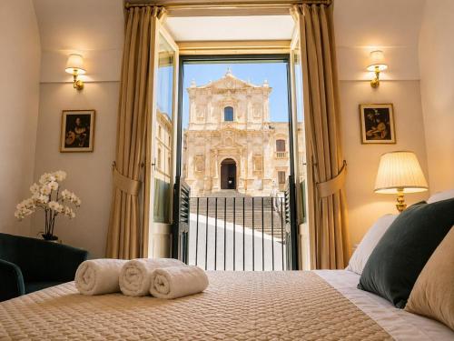 a bedroom with a bed and a view of a building at Immacolata Rooms in Noto