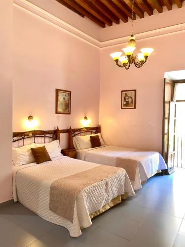 a bedroom with two beds and a chandelier at Casa del Agua in Guanajuato