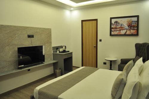 a hotel room with a bed and a flat screen tv at The Royal Palace Inn in Almora