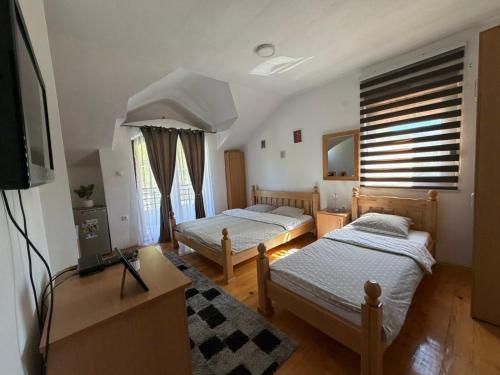 two beds in a room with a tv and a room at Vila Sana in Landeke