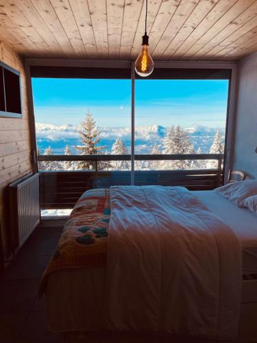 a bedroom with a bed in front of a large window at « Le doux Chalet » Roche Béranger in Chamrousse