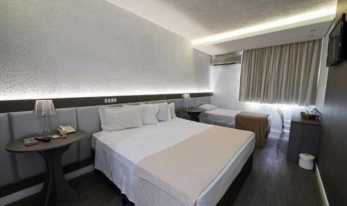 a hotel room with a large bed and a table at Dall’Onder Grande Hotel Bento Gonçalves in Bento Gonçalves