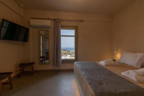 a bedroom with two beds and a large window at Onar Hotel Kimolos in Kimolos