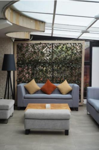 a living room with a blue couch with pillows at ApartaSuite City Bog Usaquén in Bogotá