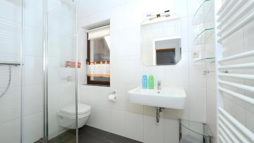 a white bathroom with a toilet and a sink at Ferienwohnung Brunk in Altefähr
