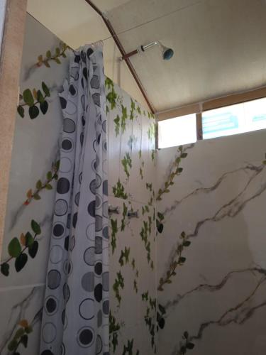a bathroom with a shower curtain with a plant at Uros Suyawi Titicaca Lodge in Puno