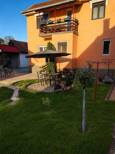 a building with a table and umbrella in the yard at Kuća Amazonija in Apatin