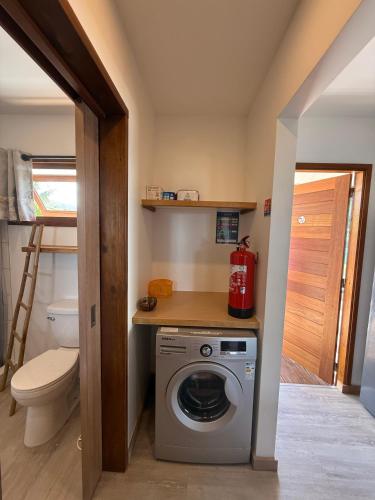 a bathroom with a washing machine and a toilet at Le Rainoa - Beach House in Taputapuapea