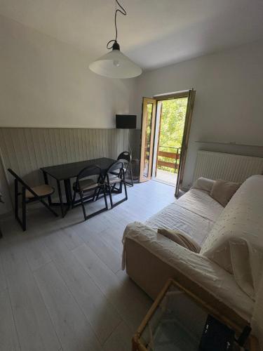 a living room with a bed and a table and chairs at Cozy Mountain Apartment with Cimone view in Faidello