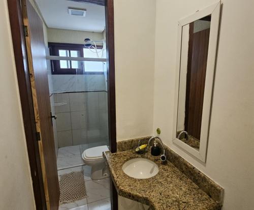 a bathroom with a sink and a toilet at Pousada Nova Flor de Lotus Suites in Tamandaré