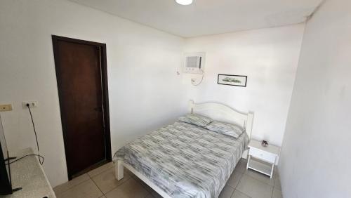 a small white room with a bed and a door at Pousada Nova Flor de Lotus Suites in Tamandaré