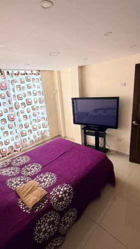 a bedroom with a purple bed and a flat screen tv at Aparta studio Zona Centro in Darién