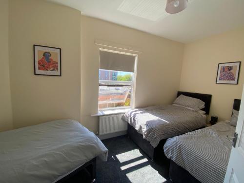 two beds in a small room with a window at Town Centre House Sleeps 8 with parking in Stafford