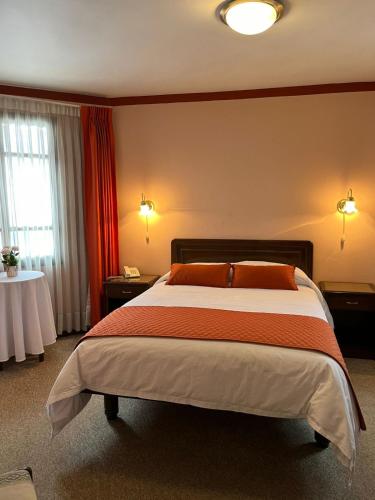 a hotel room with a large bed with orange pillows at Hotel Gran Libertador in Potosí