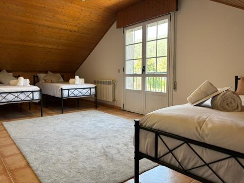 a bedroom with two beds and a large window at Villa Playa Covelo in Pontevedra