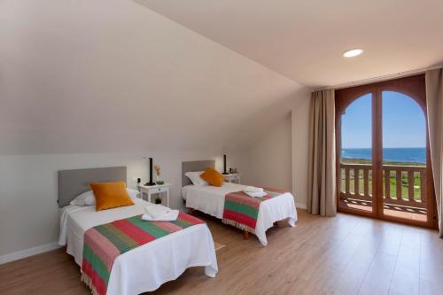 two beds in a room with a view of the ocean at Casa do Seixo in Oia