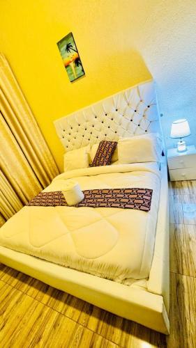 a bedroom with a large bed with a yellow wall at Montana Stay B&B in Ruhengeri