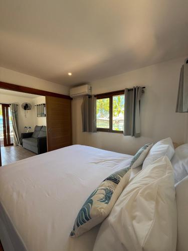a bedroom with a large white bed with a window at Le TeRava - Beach House in Ataiti