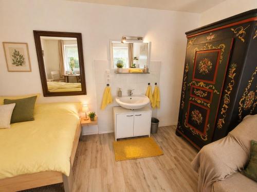 a bathroom with a bed and a sink and a mirror at Gästehaus Mohr in Eberhardzell