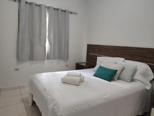 a bedroom with a large white bed with towels on it at Aconchego 3 - Self Check-in in Presidente Prudente