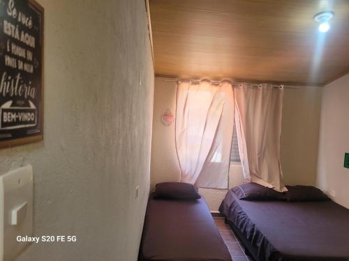 a small room with two beds and a window at Pousada do Sossego Mar e verde 3 in Itanhaém