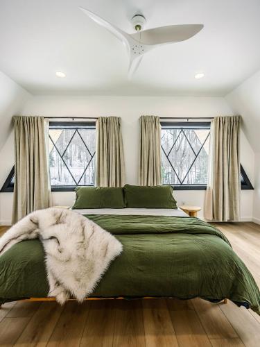a bedroom with a bed with a green comforter at Green Mountain Yay Frame in Killington