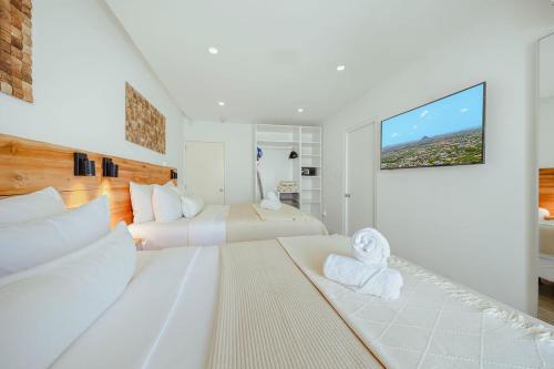 a white bedroom with two beds and a flat screen tv at Walk to Beach - Private Pool Villa in Palm-Eagle Beach