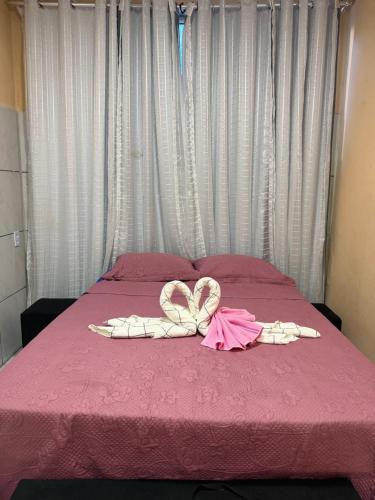 a pink bed with pink sheets and a bow on it at Sol e mar in Serra