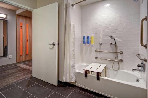 a bathroom with a tub and a shower with a bench at Tru By Hilton Raleigh Durham Airport in Morrisville