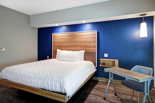 a bedroom with a bed with a blue wall at Tru By Hilton Raleigh Durham Airport in Morrisville