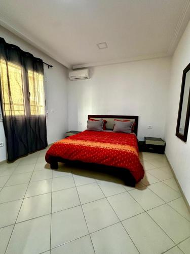 a bedroom with a bed with a red blanket at Appartement le jasmin in Hammamet