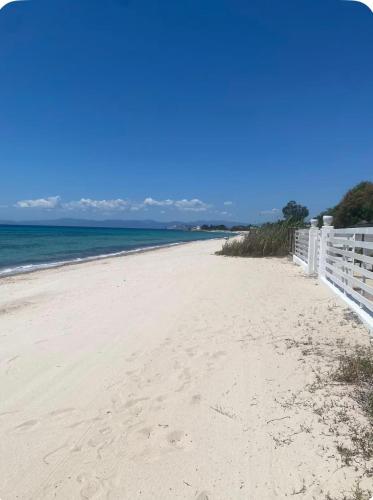 a sandy beach with a white fence and the ocean at Casa Roberta a due passi dal mare in Quartu Sant'Elena