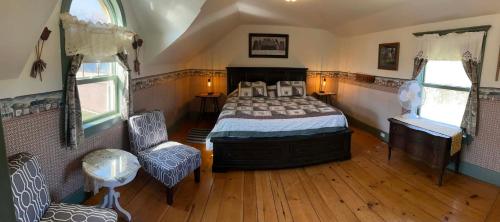 a bedroom with a bed and a chair and windows at Bugaboo Cottages in Summerside