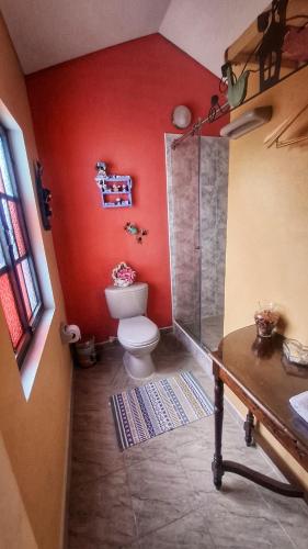 a bathroom with a toilet and a red wall at El Pedregal Sopó in Sopó