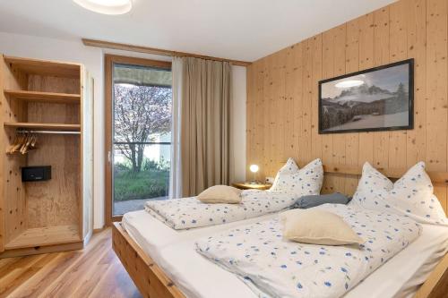 two beds in a room with a large window at Petrunderhof in Villnoss