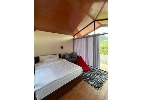 a bedroom with a large bed and a couch at D'BAGOES Luxury Cabin in Sarangan