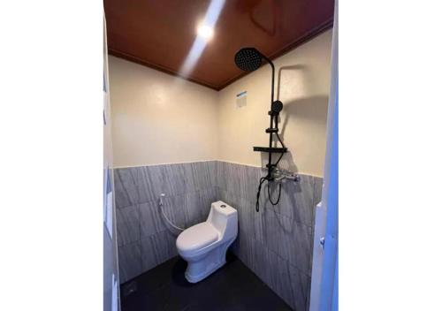 a bathroom with a toilet and a light on the wall at D'BAGOES Luxury Cabin in Sarangan
