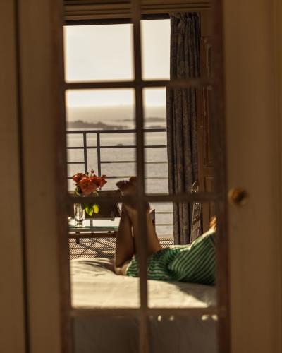 a woman laying on a bed looking out a window at Manoir de Lan Kerellec - Relais & Châteaux - Etoilé Michelin in Trébeurden
