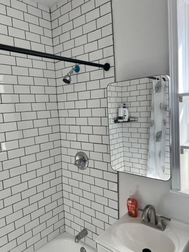 a white tiled bathroom with a sink and a mirror at Tír na nÓg in Union City