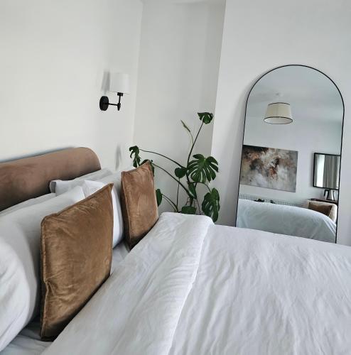 a white bed with brown pillows and a mirror at Cardiff Mini Retreat in Cardiff