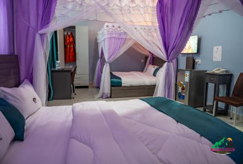a bedroom with a large bed with purple canopy at Legacy Chillout Kasese in Kasese