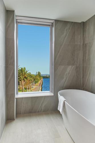 a bath tub in a bathroom with a window at Doubletree By Hilton Perth Waterfront in Perth