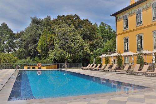 a swimming pool in front of a yellow building at Boeira Garden Hotel Porto Gaia, Curio Collection by Hilton in Vila Nova de Gaia
