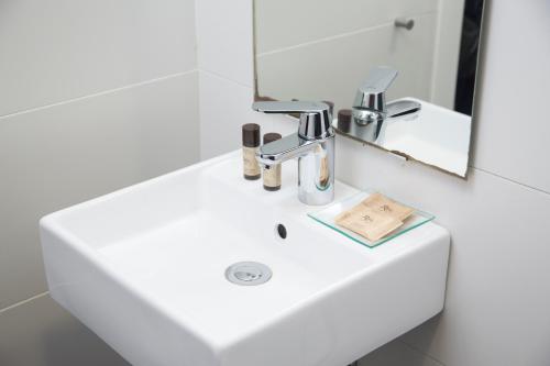 a bathroom sink with a faucet and a mirror at Apartamentos Córdoba Best II in Córdoba