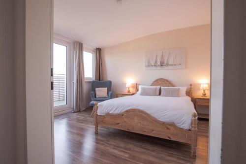 a bedroom with a large bed and a blue chair at Landhotel Strandallee in Wunstorf
