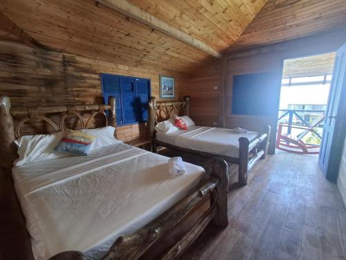 a bedroom with two beds in a wooden cabin at Hotel Isla Gaviota in Tintipan Island
