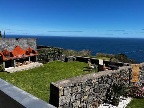 a garden with a stone wall and the ocean at Oásis Fonte Grande in Santo António