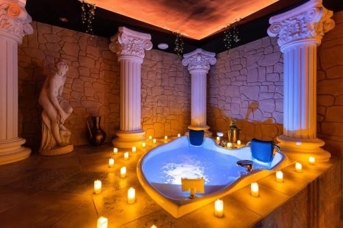 a bathroom with a tub with candles and a statue at La Suite de Vénus - Chambre à thème Love Room Jacuzzi et Pièce Secrète - Évasion pour deux in Schirrhein